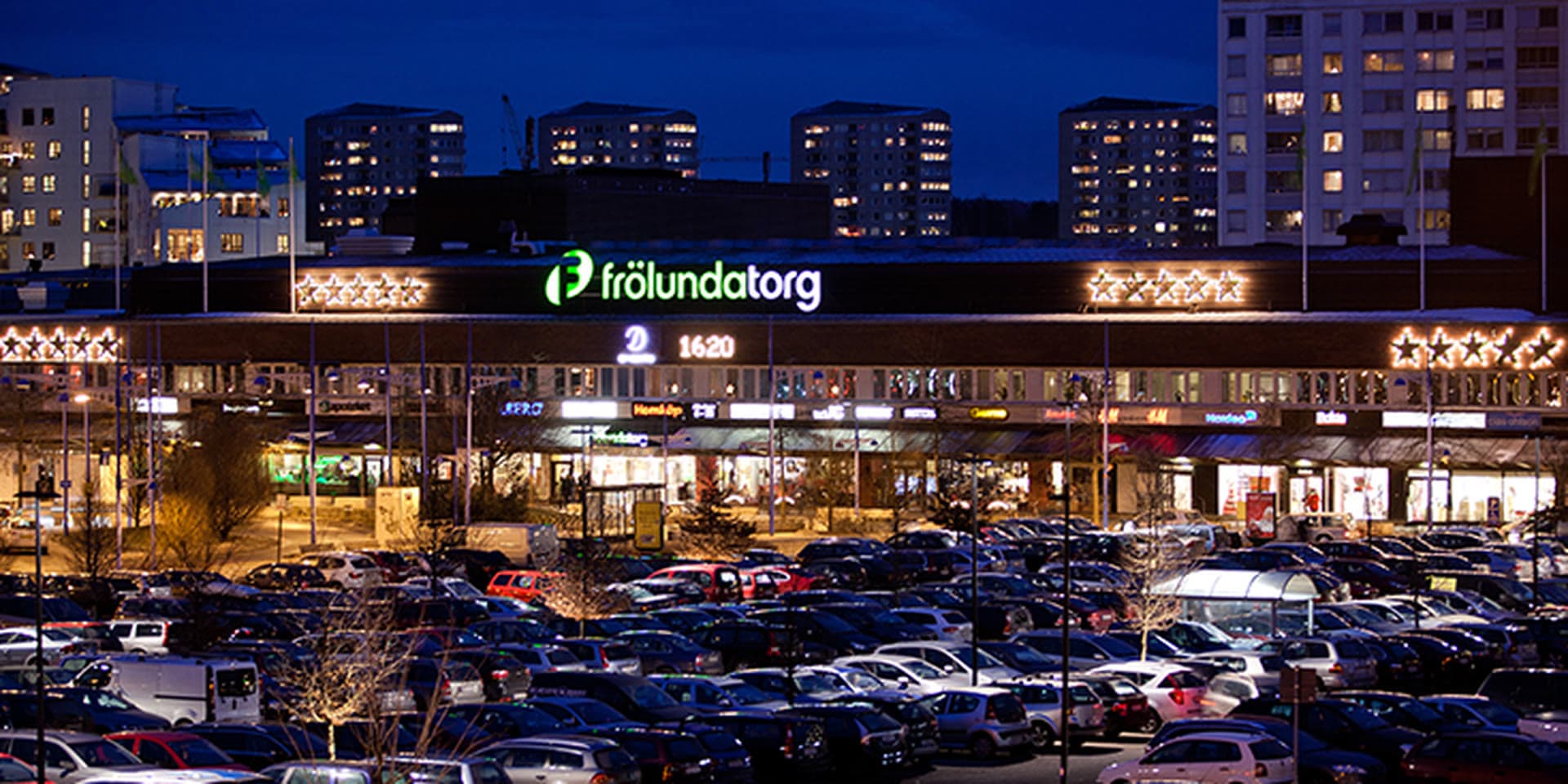 Askim-Frölunda-Högsbo, Göteborg — Frölunda Torg på kvällen med upplyst köpcentrum och flerfamiljshus. Hitta privatägda veterinärer och djurkliniker i Askim-Frölunda-Högsbo.